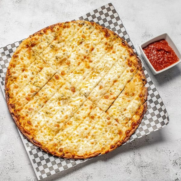 Round cheesy garlic breadsticks, cut into squares, with a side of red marinara sauce on a checkered paper.